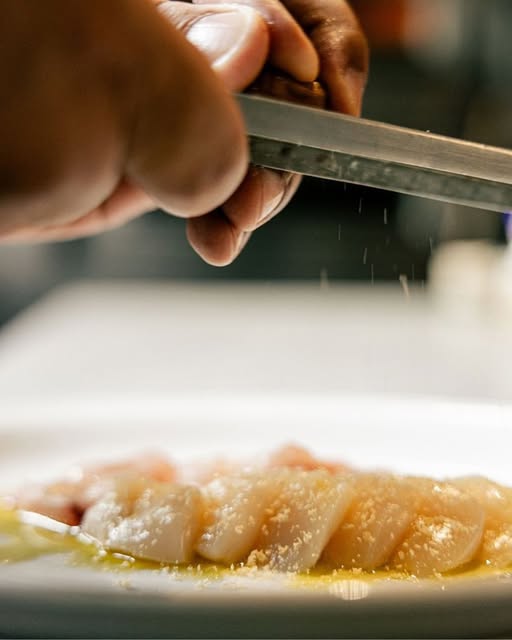 Chef finishing a fish dish at AURA by Bianco